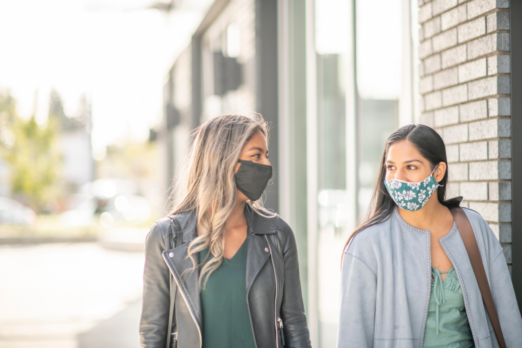 two women walking outside and wearing face masks